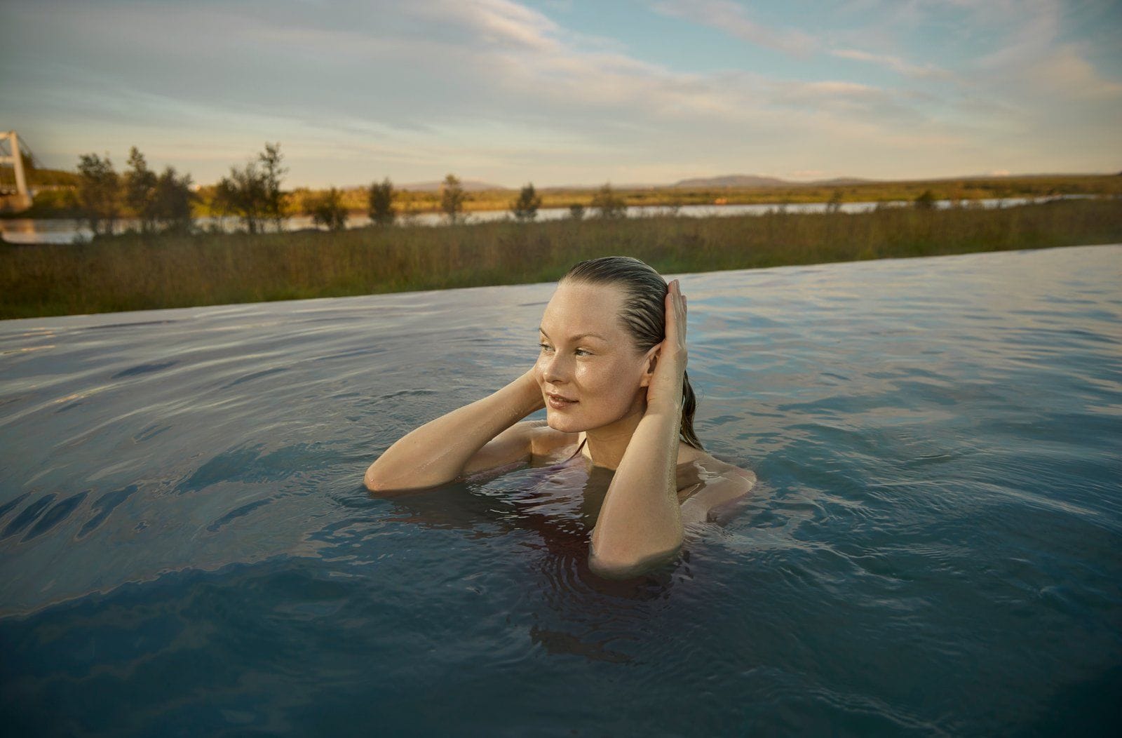 woman relaxing in Laugarás Lagoon surrounded by nature