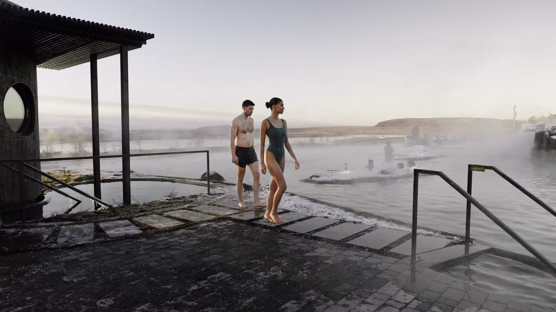 Two guests walking into the warm lagoon in morning mist