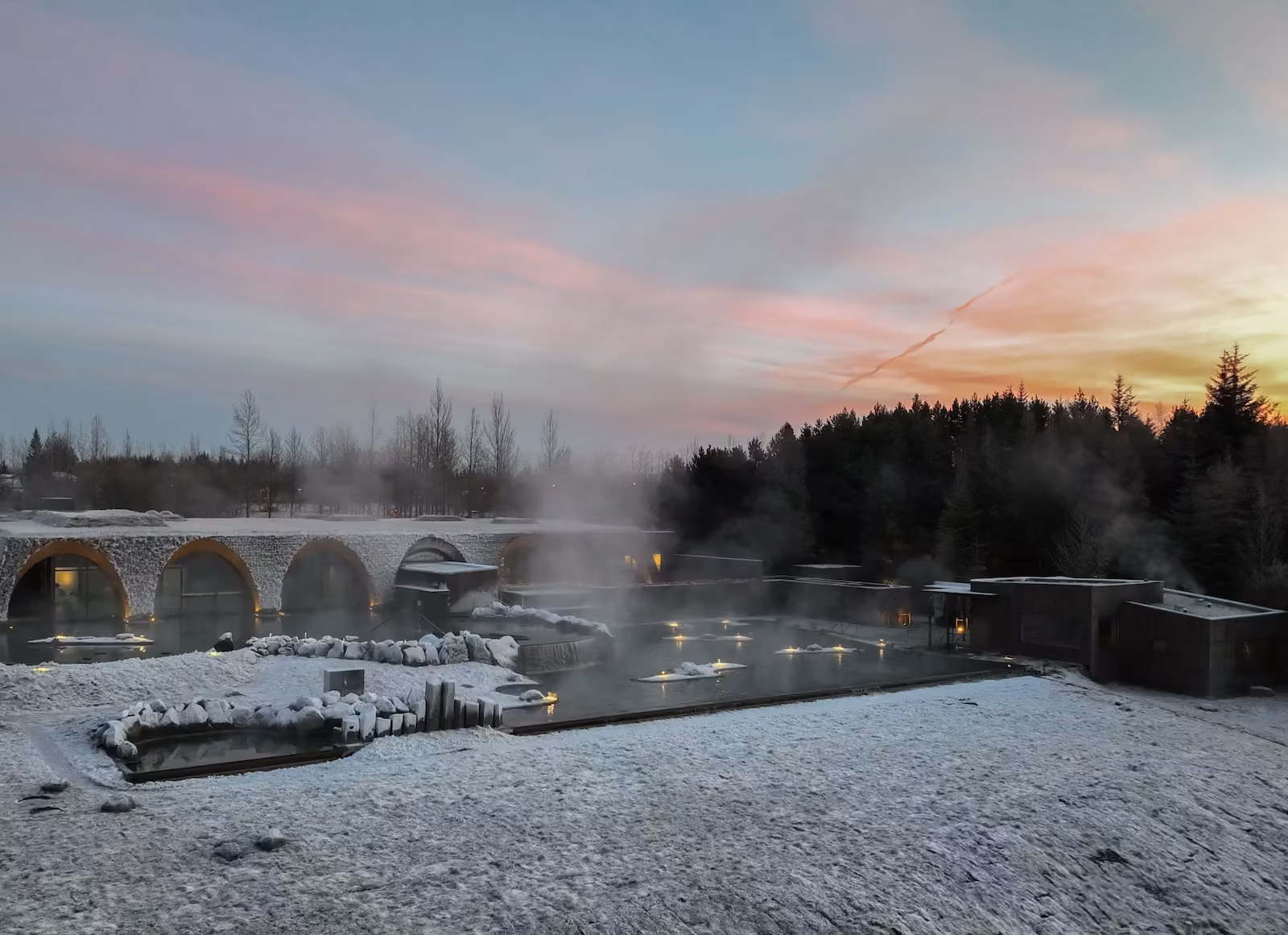 Laugarás Lagoon in winter at sunset, with steam rising from the lagoon